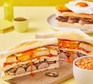 Two breakfast club sandwiches with a bowl of beans alongside