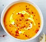 Bowl of carrot & ginger soup sprinkled with cayenne pepper