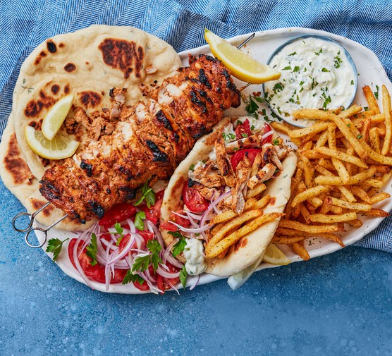 Chicken gyros on plate with pitta, chips and salad