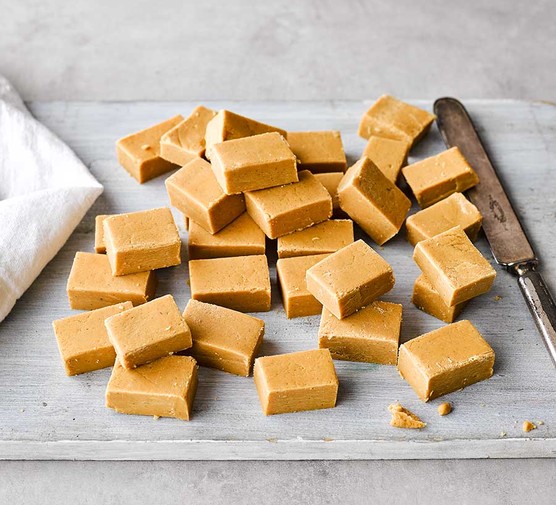 Pieces of classic fudge on a grey board with a knife