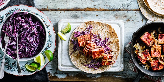 High-protein vegan recipes Curried tofu wraps on a board with shredded cabbage and fresh lime