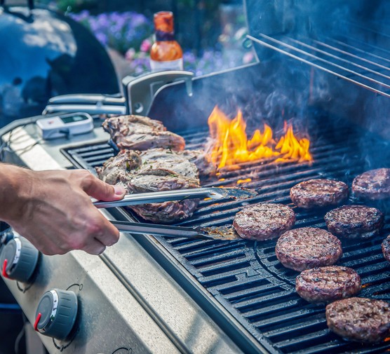 Best gas BBQs Marinated lamb joint and beef burgers cooking on an outdoor barbecue