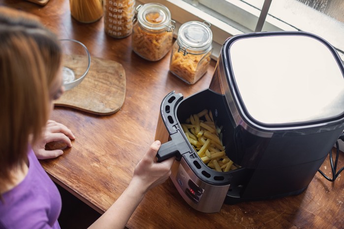 Teenage girl using an air fryer in the kitchen Best air fryers