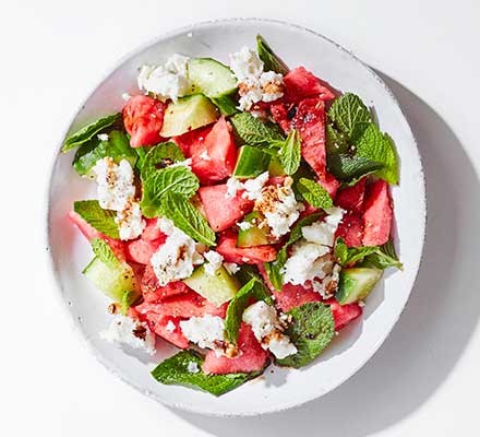 A bowl of watermelon & feta salad garnished with mint leaves