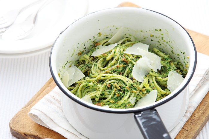Pot of spaghetti with green pesto and parmesan shards