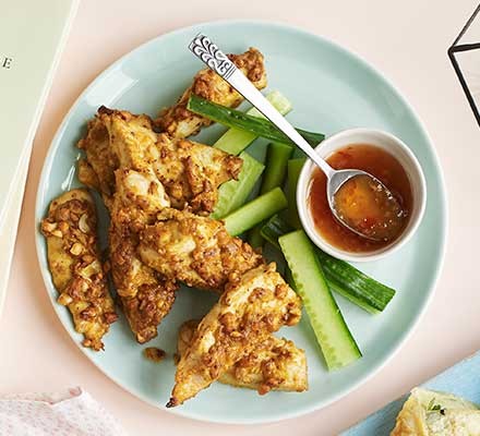 A plate of chicken satay with sliced cucumber and sweet chilli dip