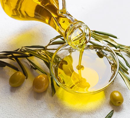 A bottle of olive oil being poured into a small bowl