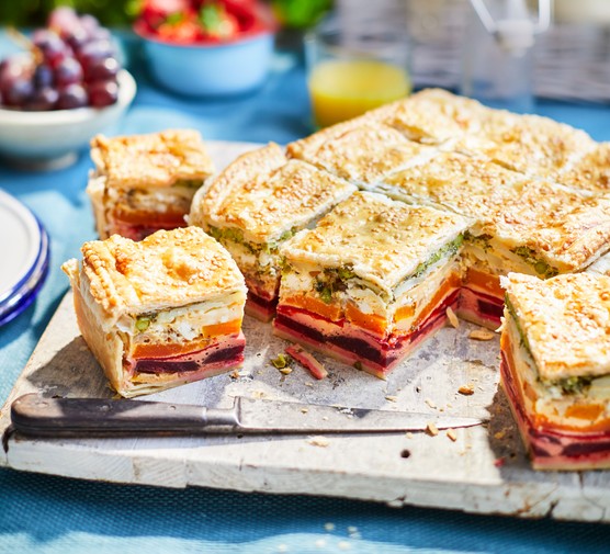A layered vegetable pie cut into squares on a chopping board