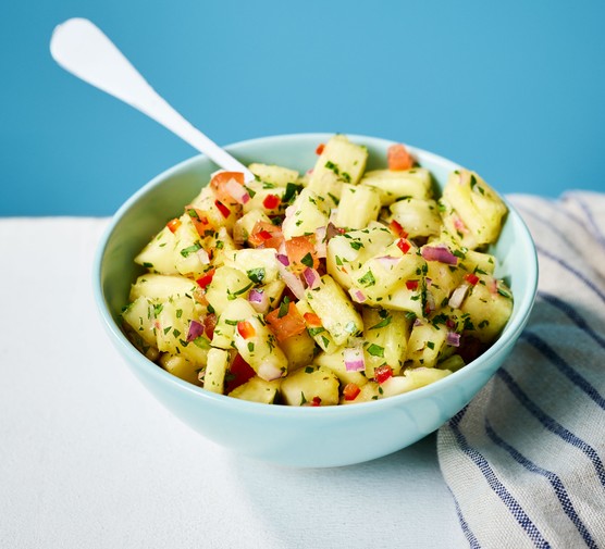 A bowl of pineapple salsa with a spoon sticking out from it