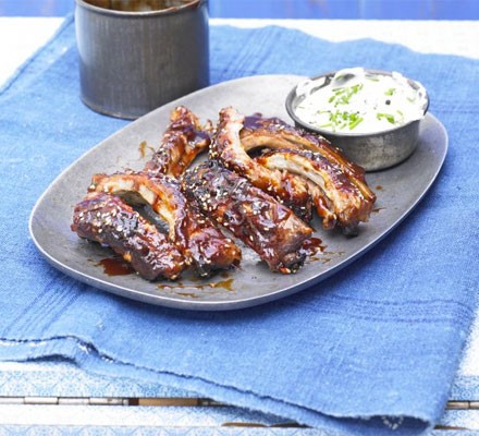Sticky BBQ ribs on a plate with a dip