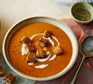A bowl of roasted red pepper soup with crispy croutons