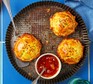 Three round pastry pies on a fluted tin with a small bowl of mango chutney on the side