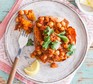 Vegan chickpea curry jacket potato on a plate with a slice of lemon and fork alongside