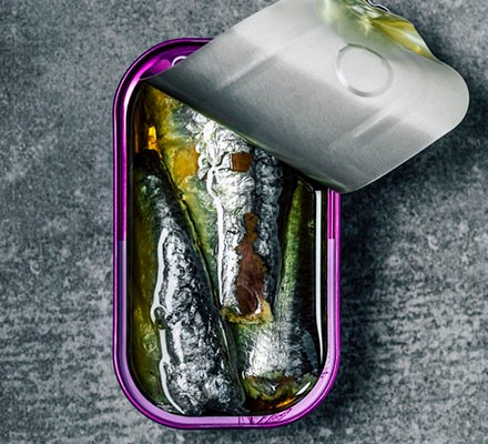 Opened can of sardines in olive oil on grey background