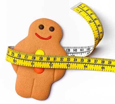 A gingerbread person with a tape measure around their waist