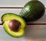 Two avocados, one cut in half with the stone visible